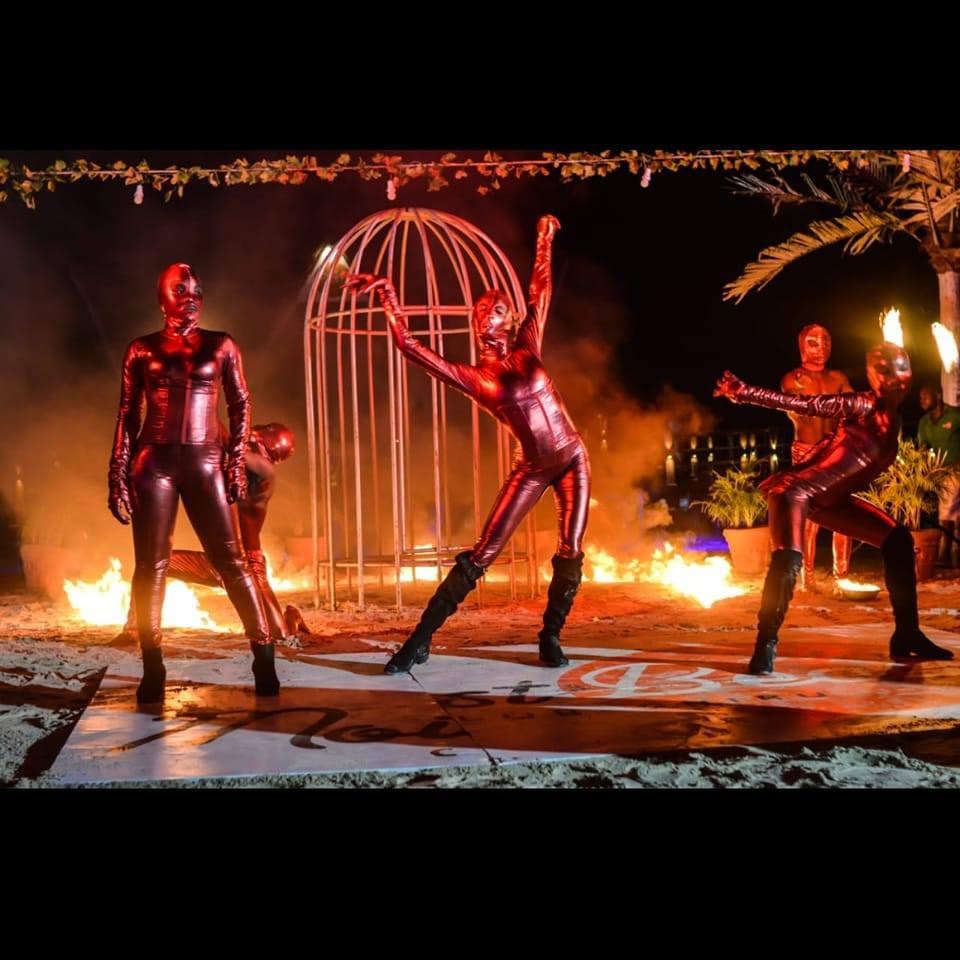 Performers in red metallic costumes surrounded by fire