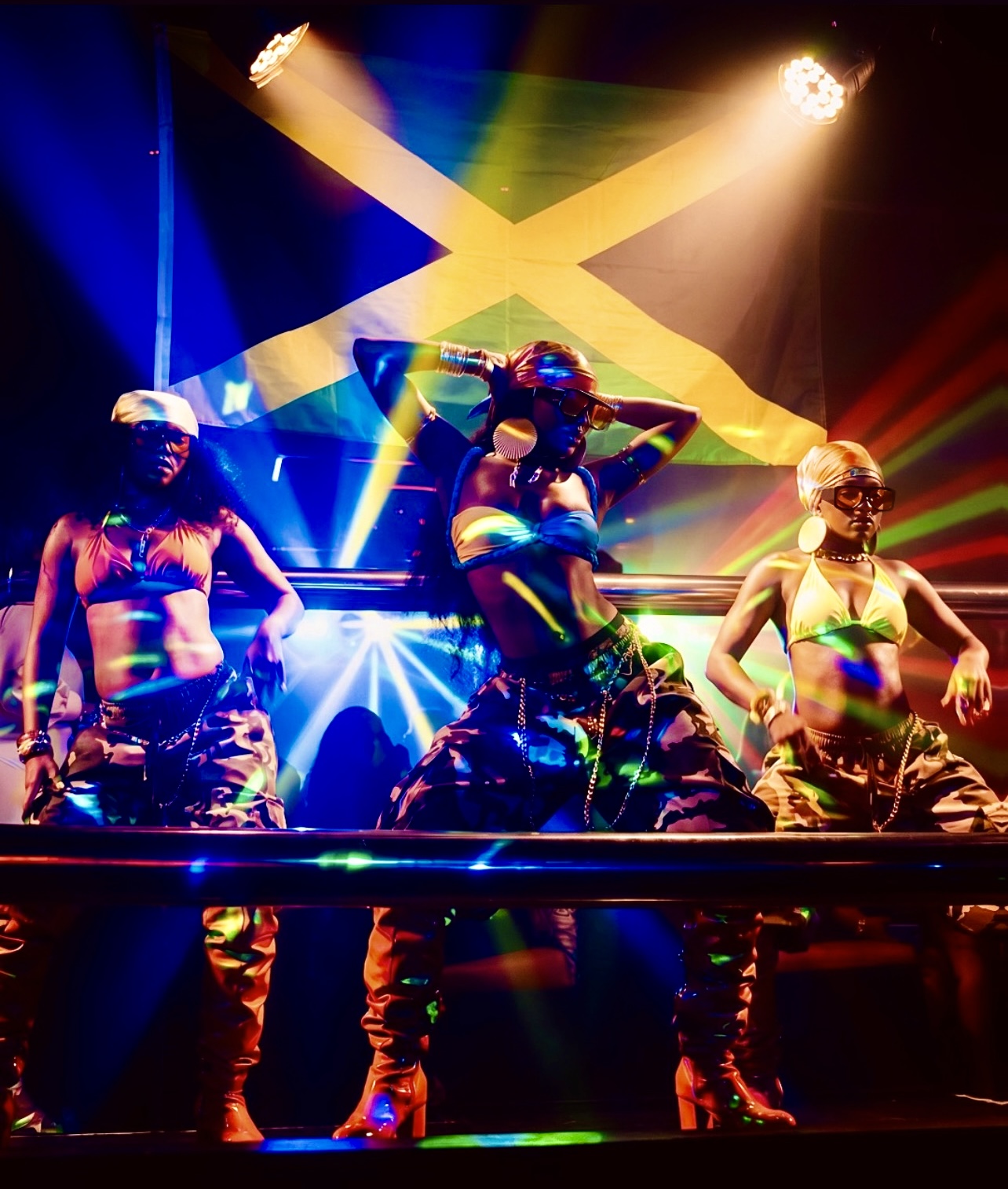 Dancers performing in front of a Jamaican flag under laser lighting